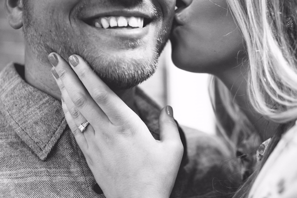 Loving kiss of an engaged couple in black and white