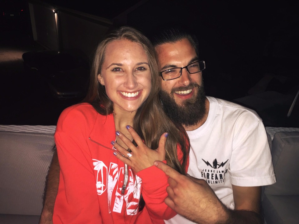 Engaged couple smiles showing engagement ring