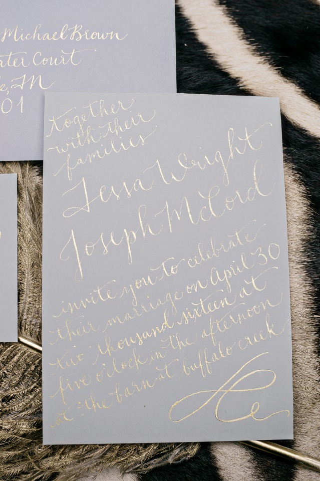 gold calligraphy wedding invite on grey paper