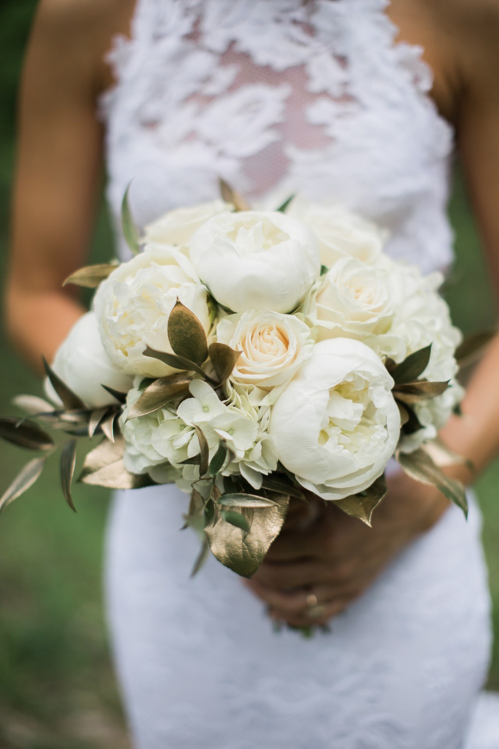 Bride holds a white peony and rose wedding bouquet