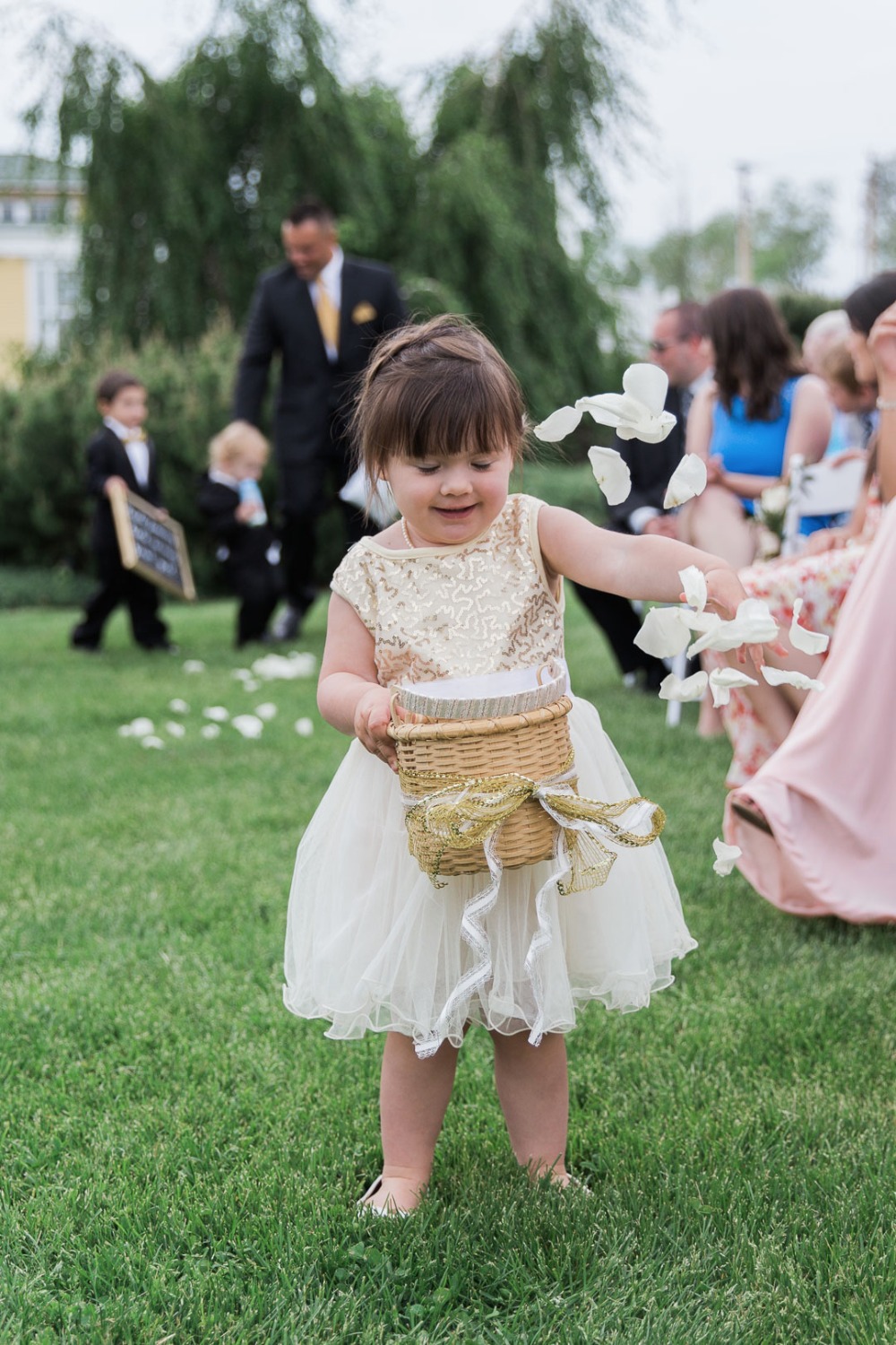 Flower girl throws petals at an outdoor wedding ceremony