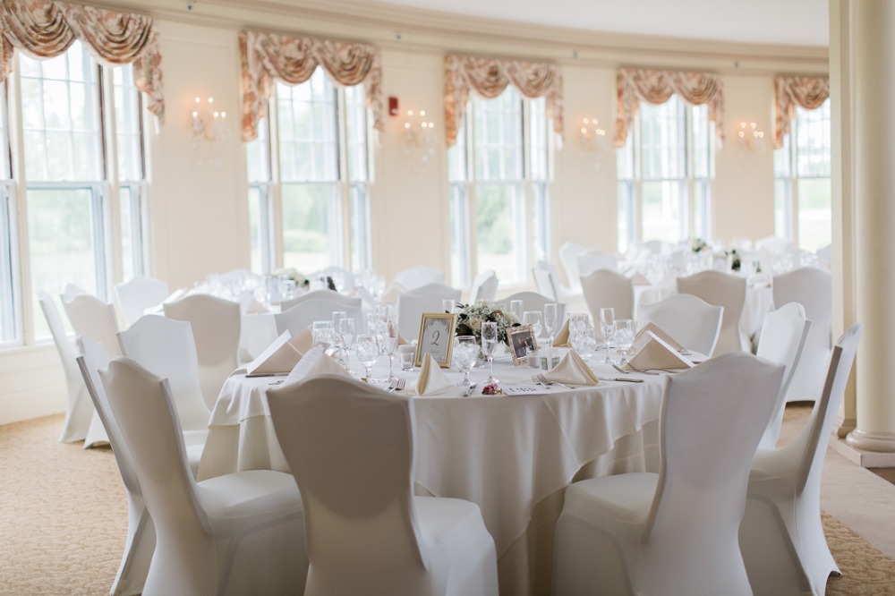 Elegant wedding reception room with round tables and white chairs
