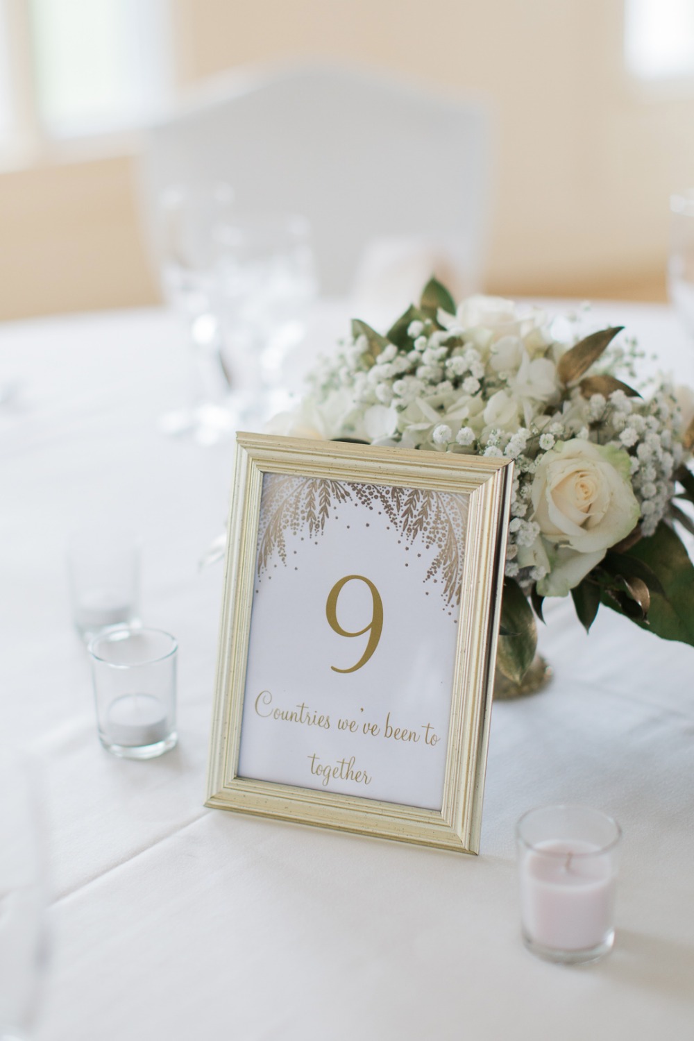 Wedding table sign displaying number 9, countries together with flowers