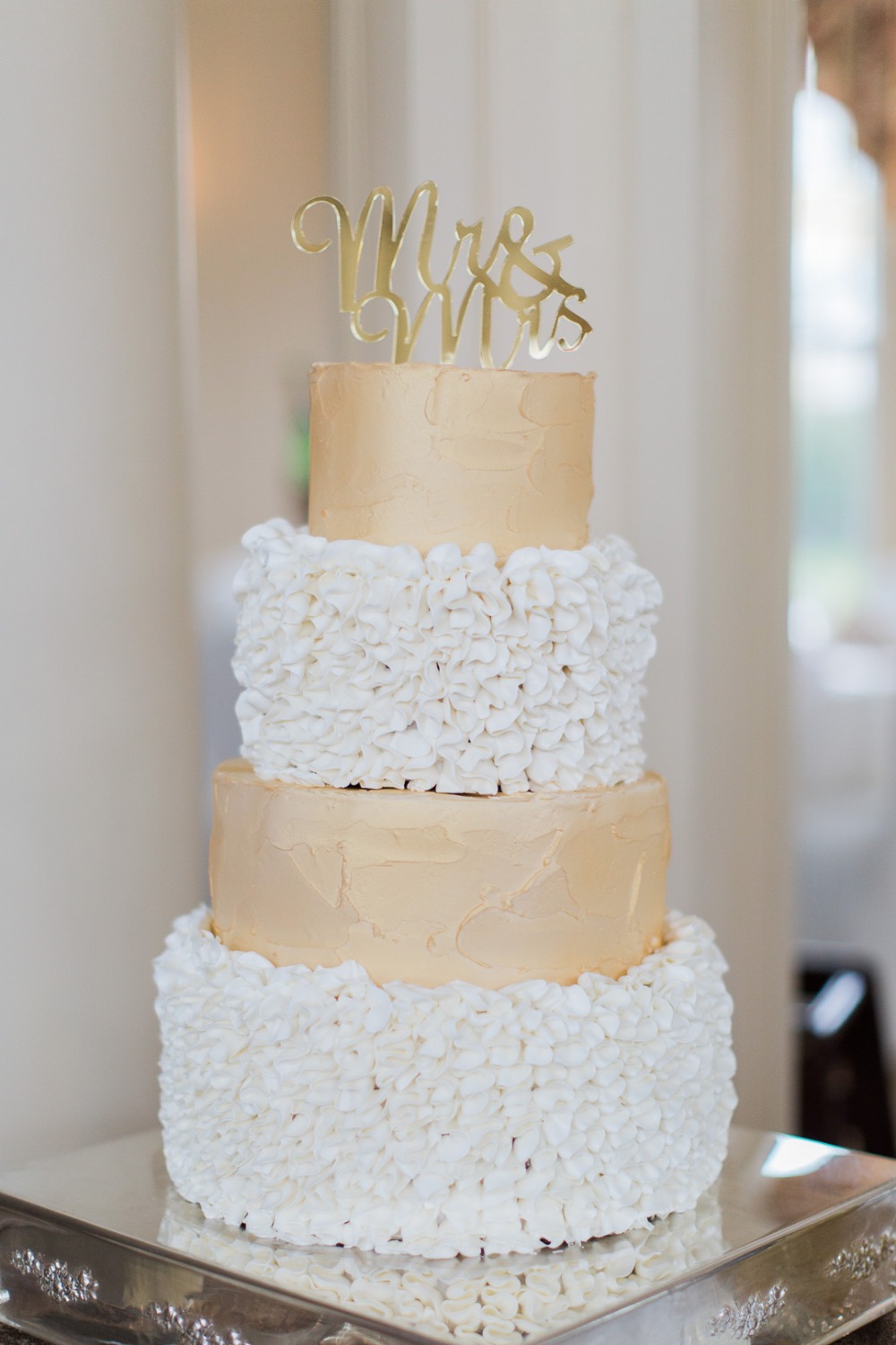 Elegant four-tiered wedding cake with Mrs Mrs gold topper