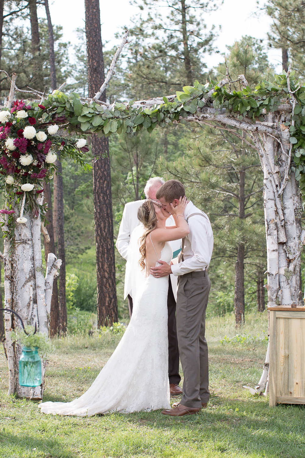 wedding kiss with wooden wedding arch