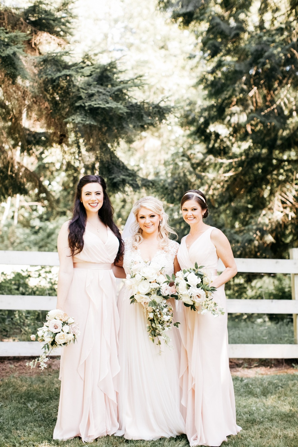 Bride with bridesmaids in blush pink gowns outdoors