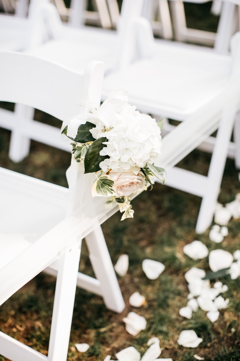 White wedding chairs decorated with flowers and ribbons