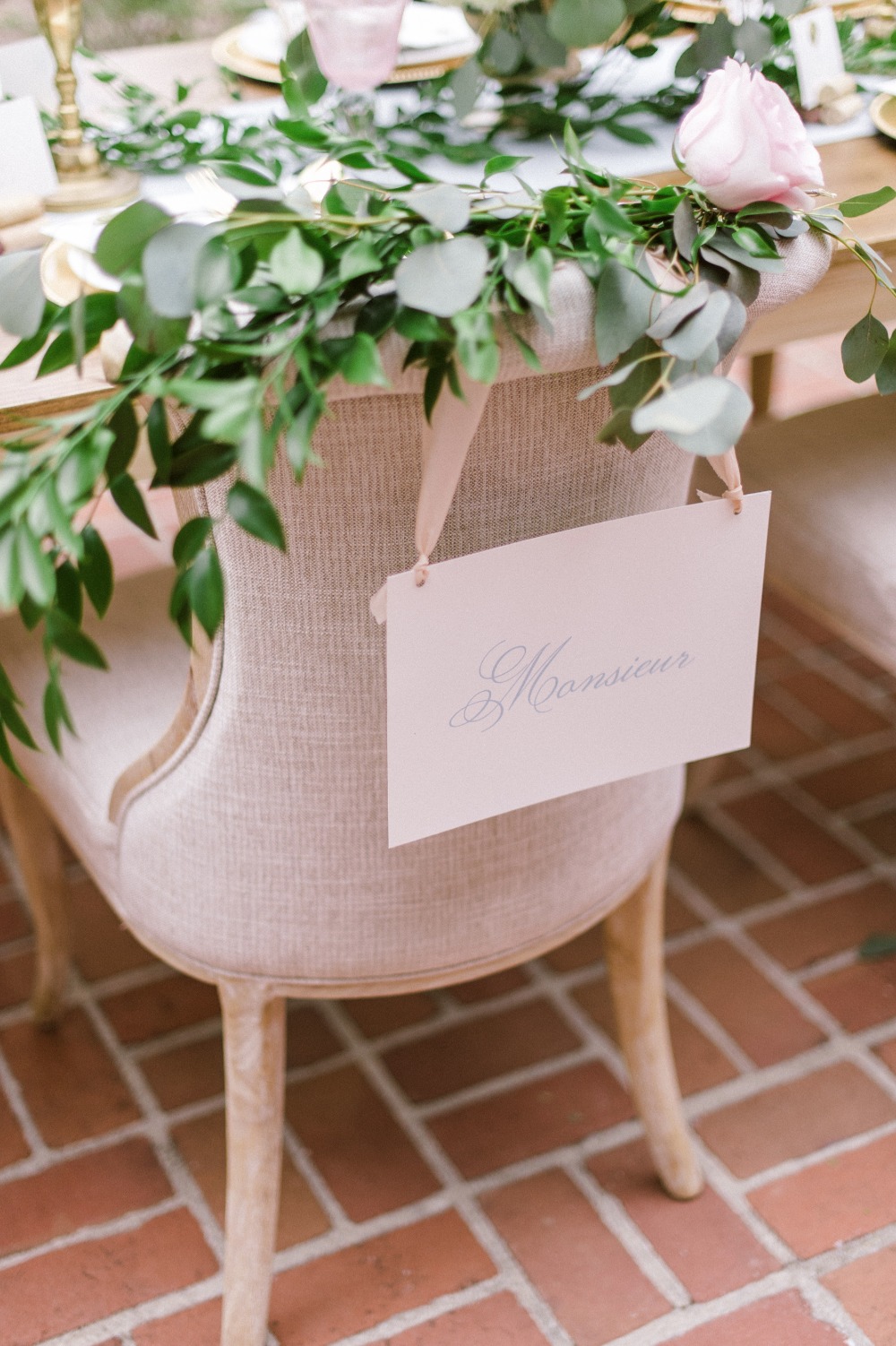 Mounsieur groom seat sign draped in a flower garland