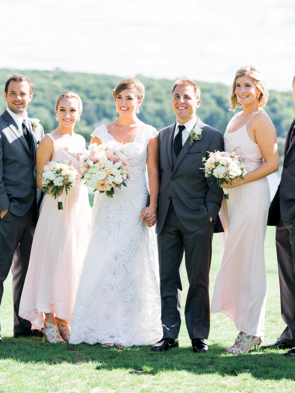 Happy wedding party posing outdoors in formal attire