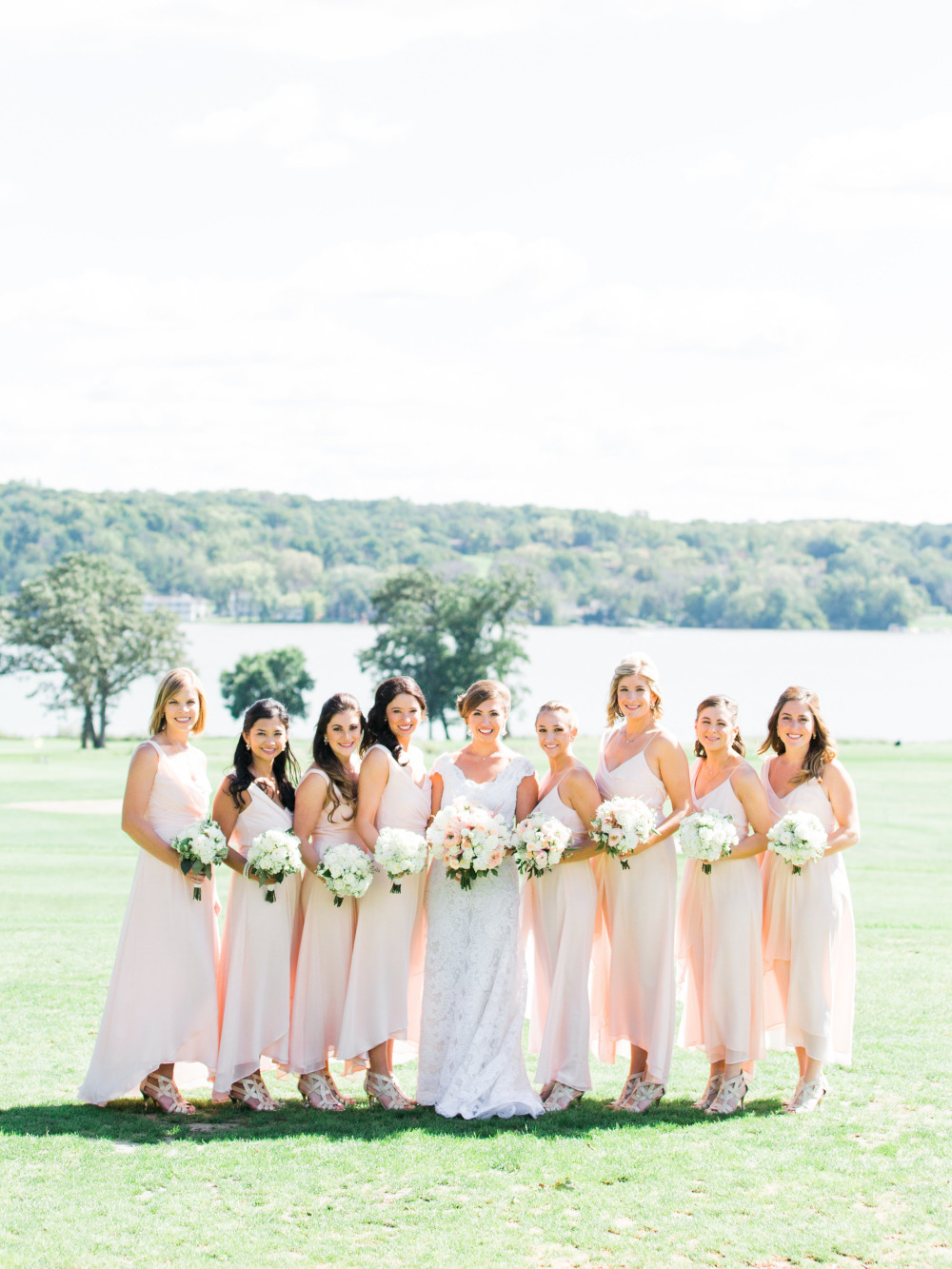 Bride and bridesmaids in pink dresses pose outdoors