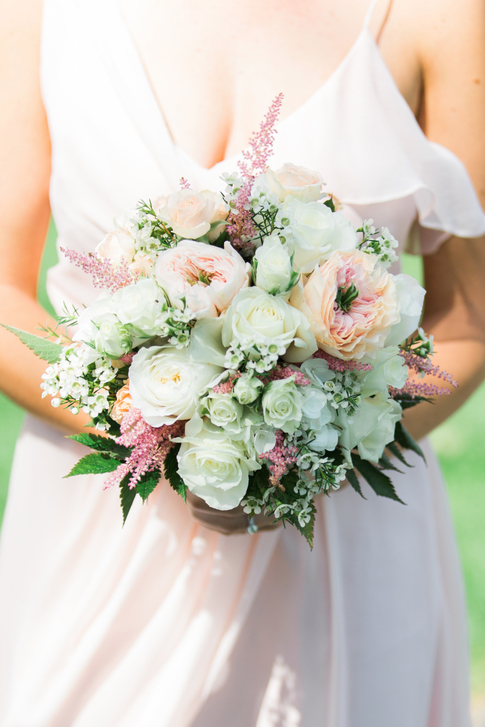 Bridesmaid holding a pastel floral bouquet in blush dress
