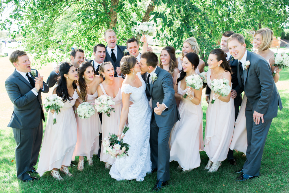 Bride and groom kissing surrounded by wedding party