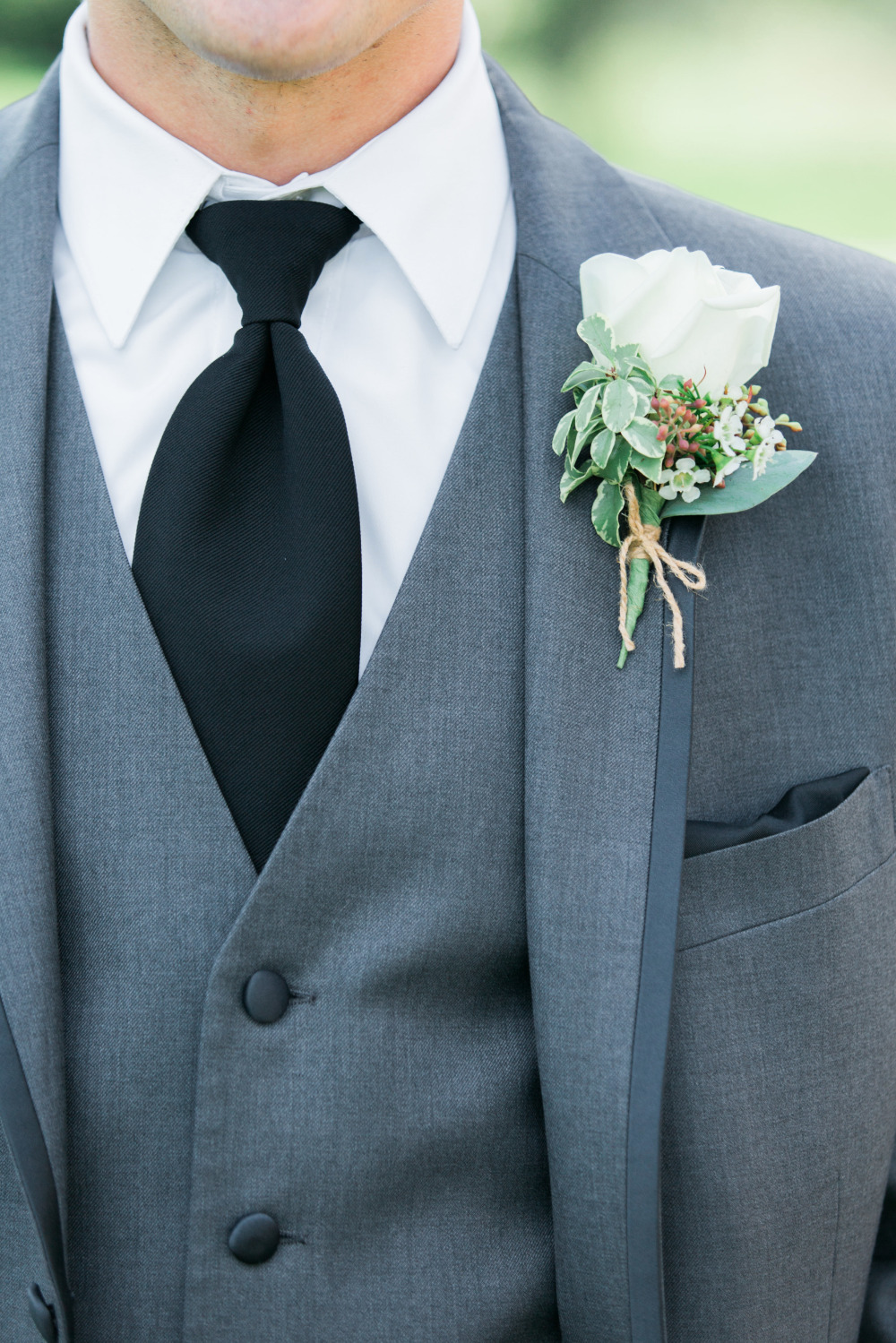 Grooms gray suit with black tie and white rose boutonniere