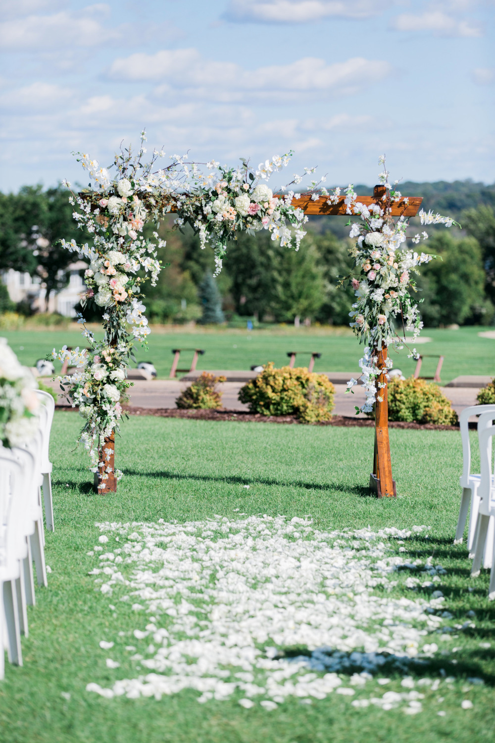 Floral wedding arch with white rose petals aisle outdoors