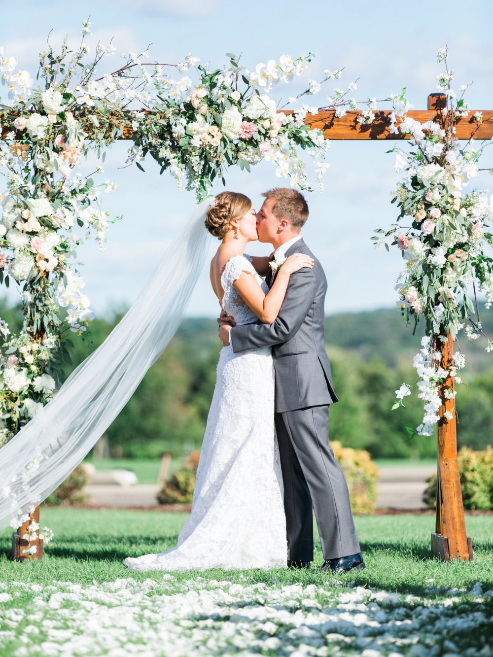 Bride and groom kissing under a floral wedding arch