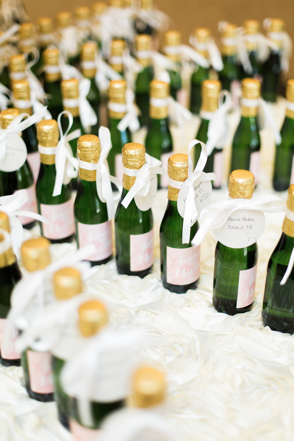 Mini champagne bottles with personalized tags for wedding reception table