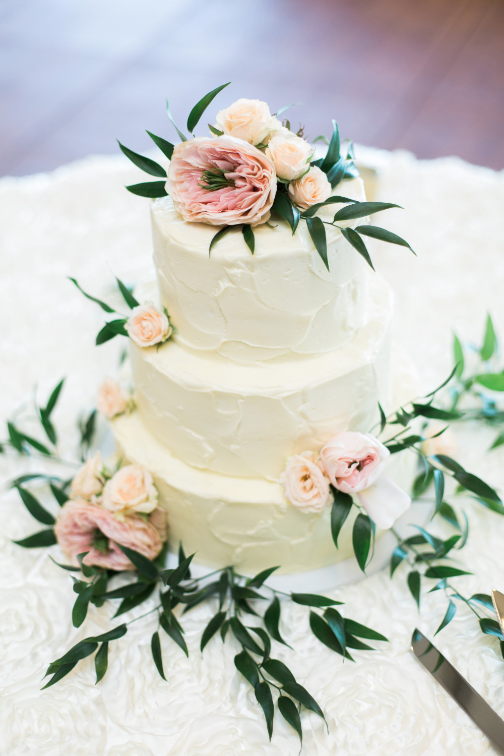 Three tier wedding cake decorated with flowers and greenery