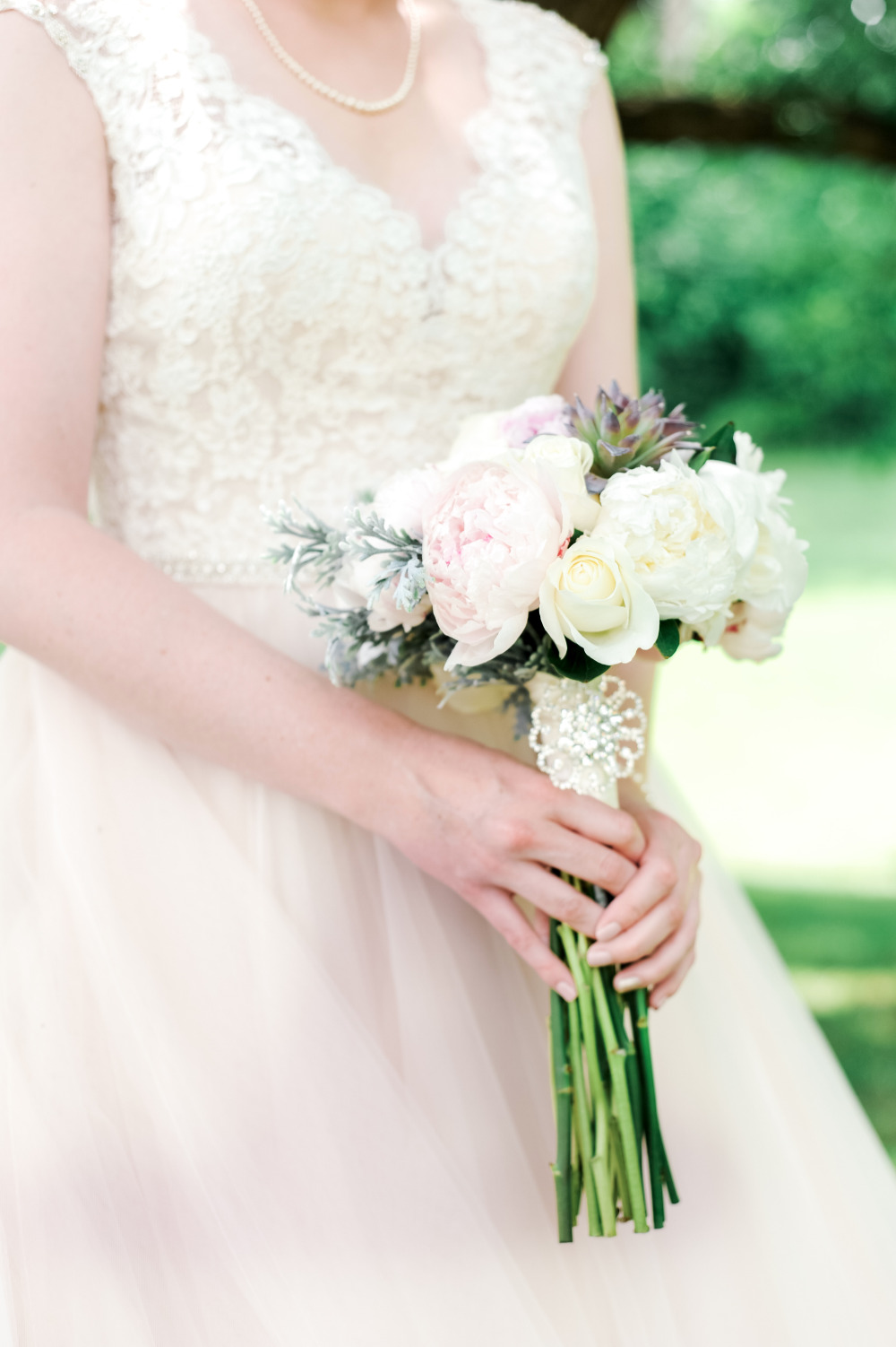 Bride in lace gown holding peony and succulent bouquet