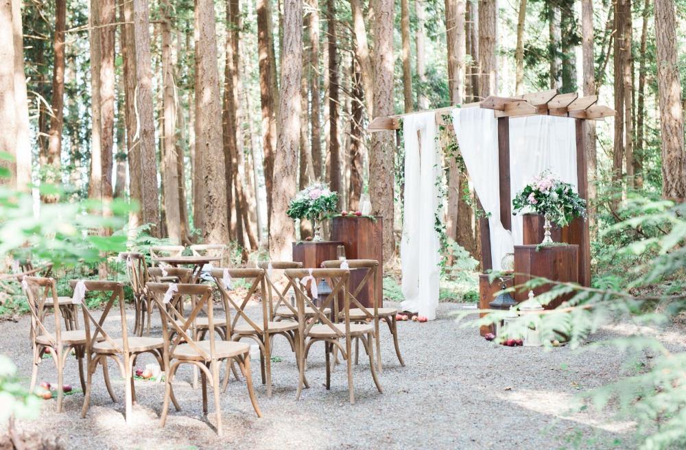 Rustic forest wedding ceremony setup with wooden chairs