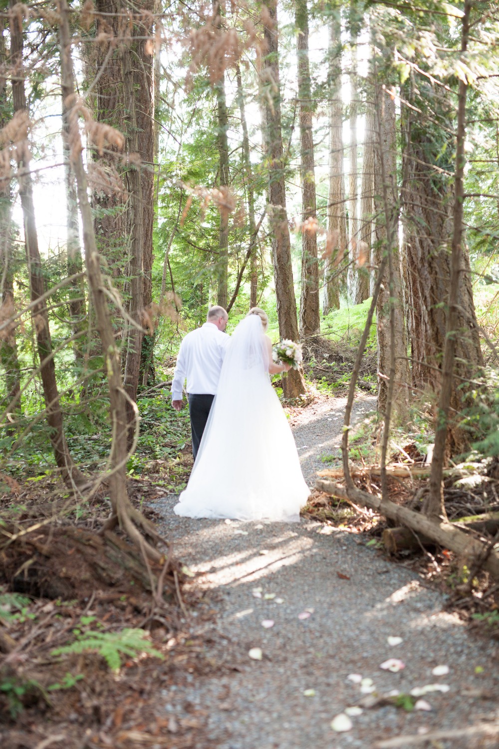 Bride and father walking down forest aisle at wedding