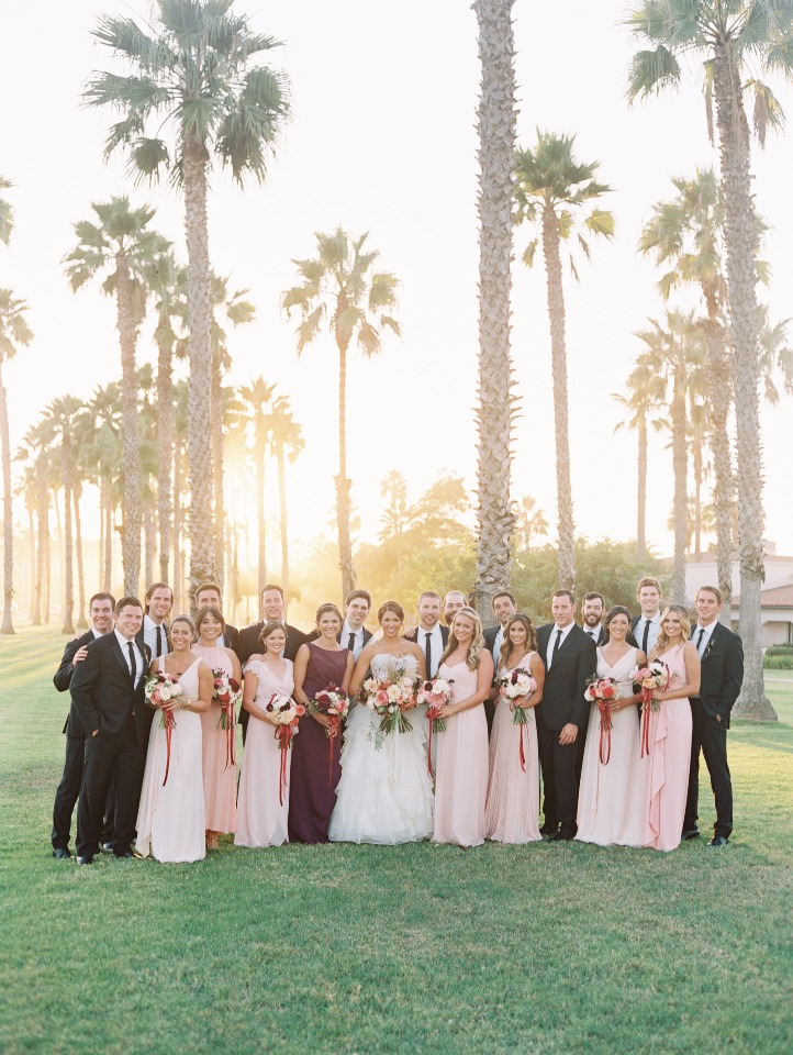 Wedding party posing on the lawn with palm trees in the background