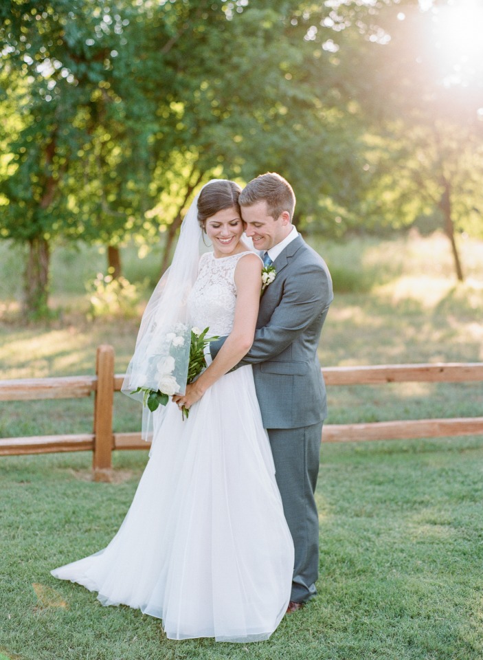 Happy couple embracing on their wedding day outdoors near a fence