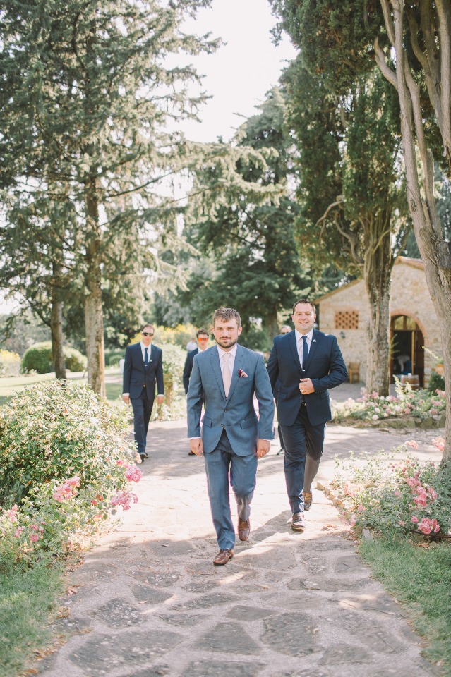 Groom and groomsmen walking towards the ceremony outdoors