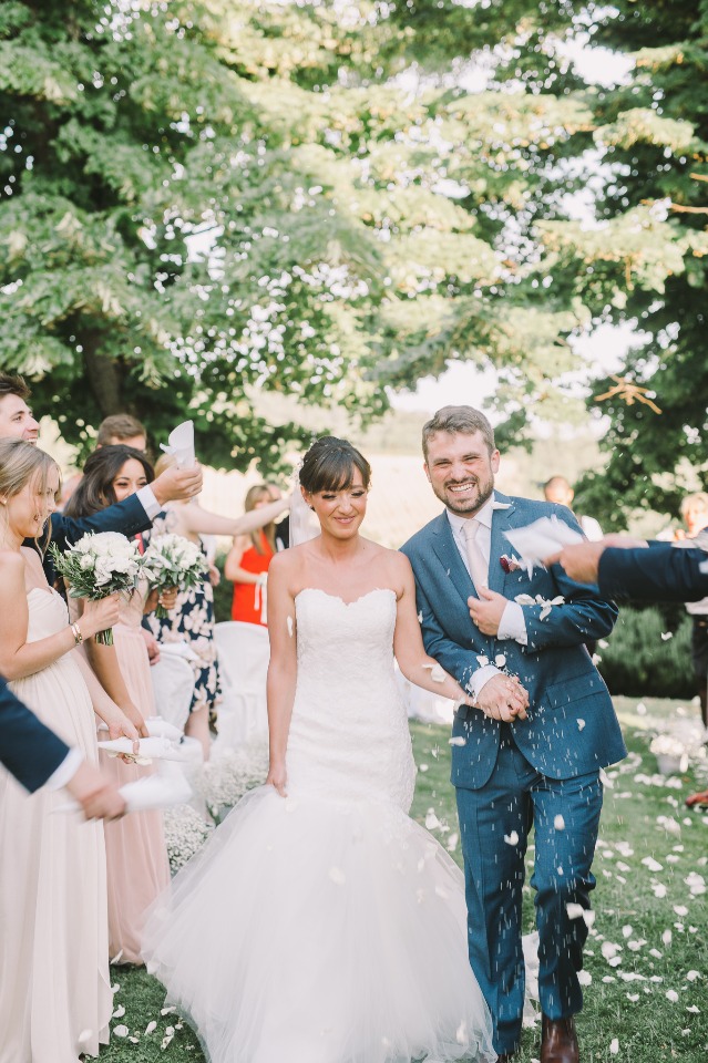 Newlyweds smiling as guests shower them with petals