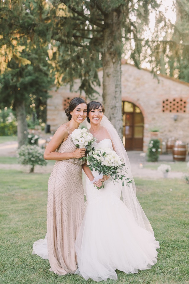Bride and bridesmaid with white flower bouquets smiling