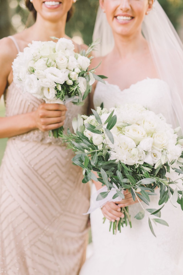 Bride and bridesmaid holding white floral bouquets