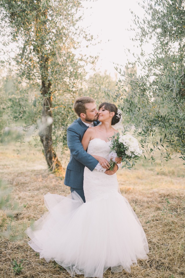 Bride and groom share a kiss in olive grove wedding