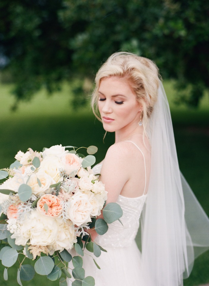Bride with a veil holding pastel bouquet of flowers
