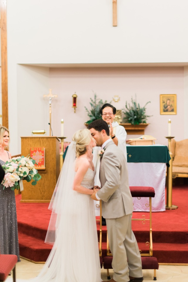 Bride and groom share a kiss at the altar during their wedding ceremony