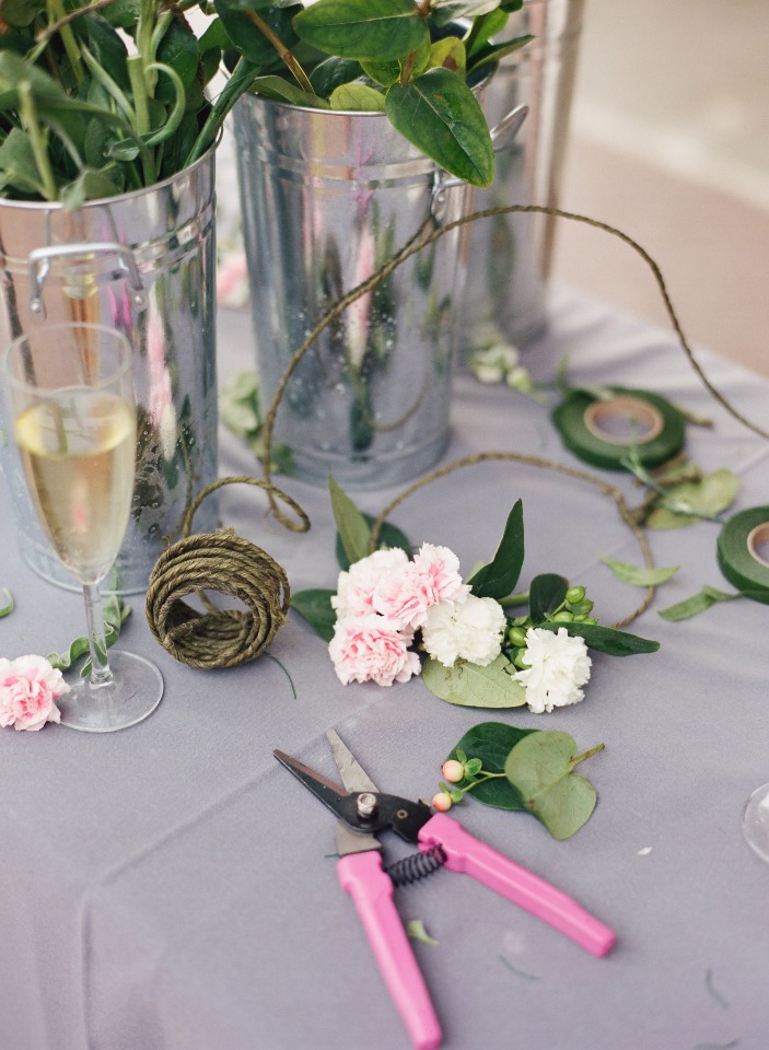 Floral arrangement supplies on table with flowers, tools and champagne