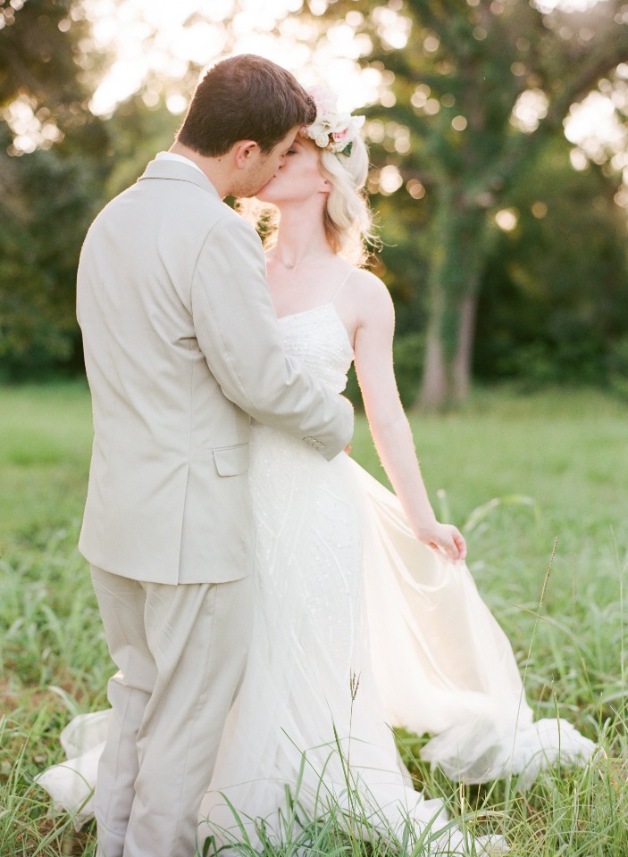 Romantic wedding couple kissing in a field of green grass