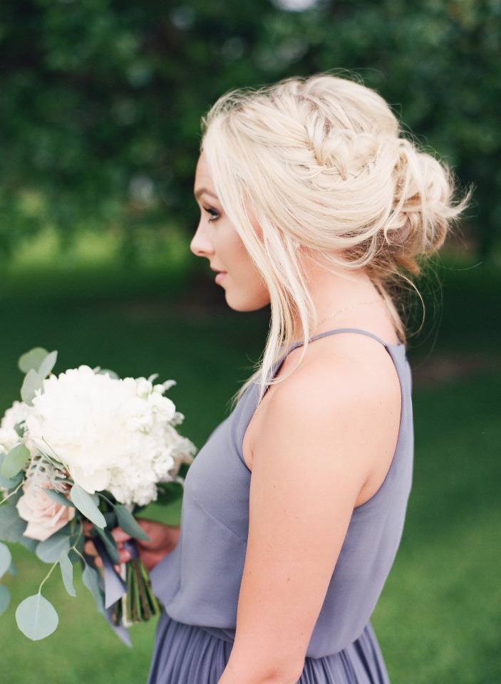 Blonde bridesmaid with braided updo holding flowers