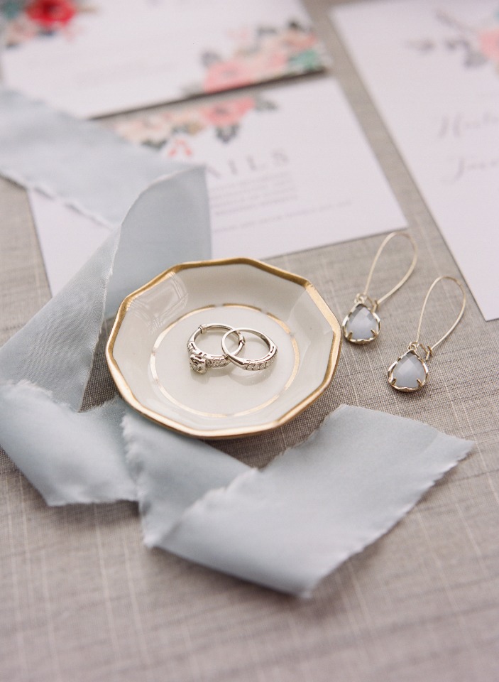 Wedding rings on a dish with blue ribbon and earrings