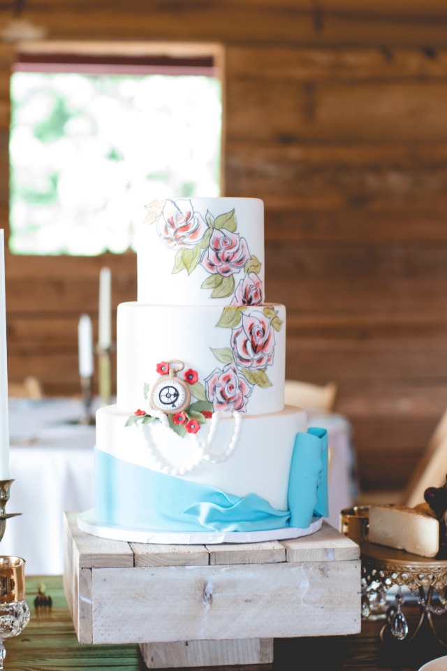 Floral painted wedding cake with blue bow
