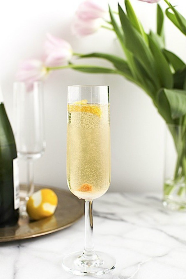 Champagne flute with lemon twist and flowers on table