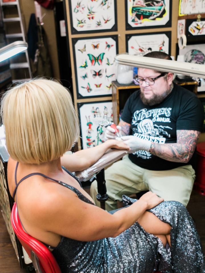 Woman getting a tattoo on her arm at a tattoo parlor
