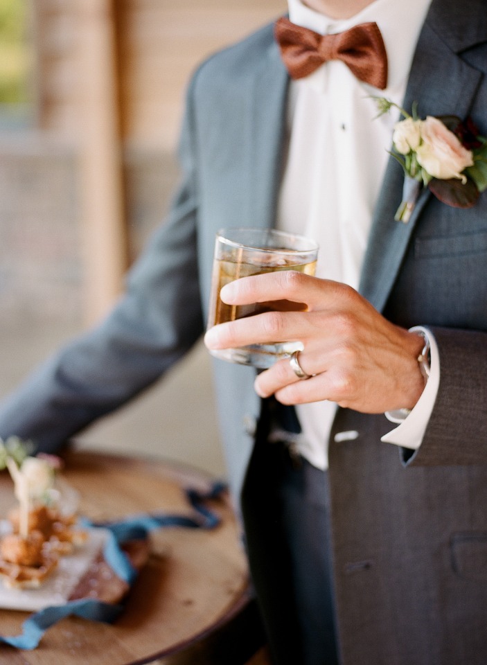 Groom in suit holding a drink at a wedding celebration