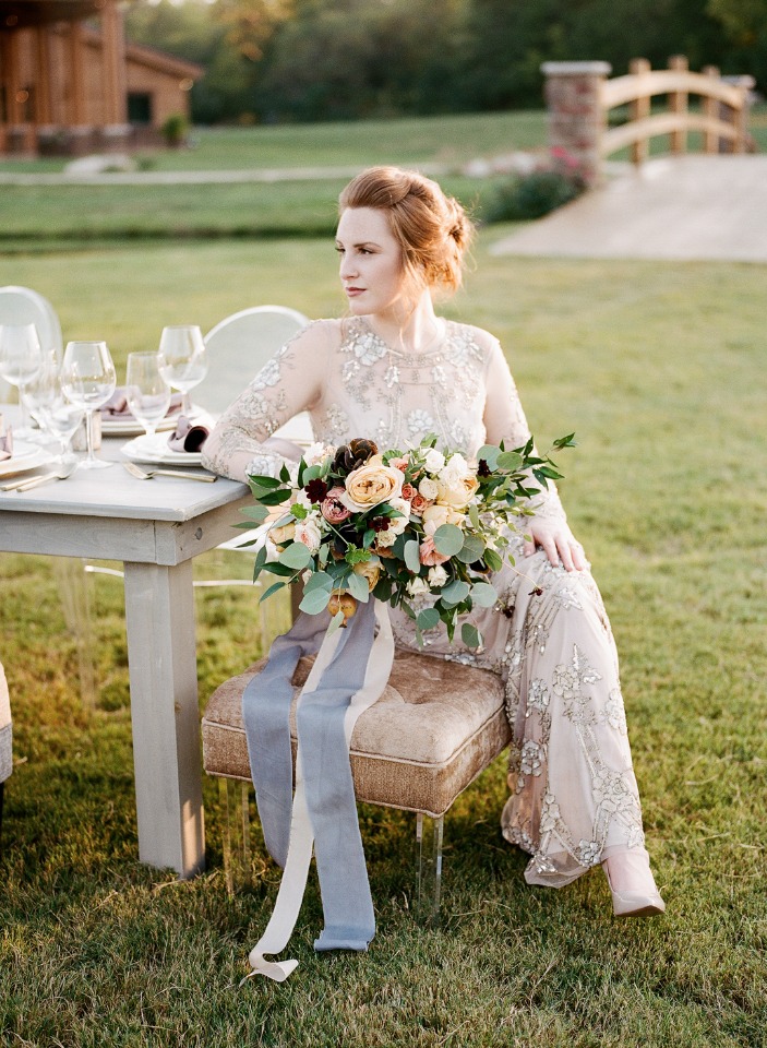 Elegant bride seated with bouquet at outdoor wedding