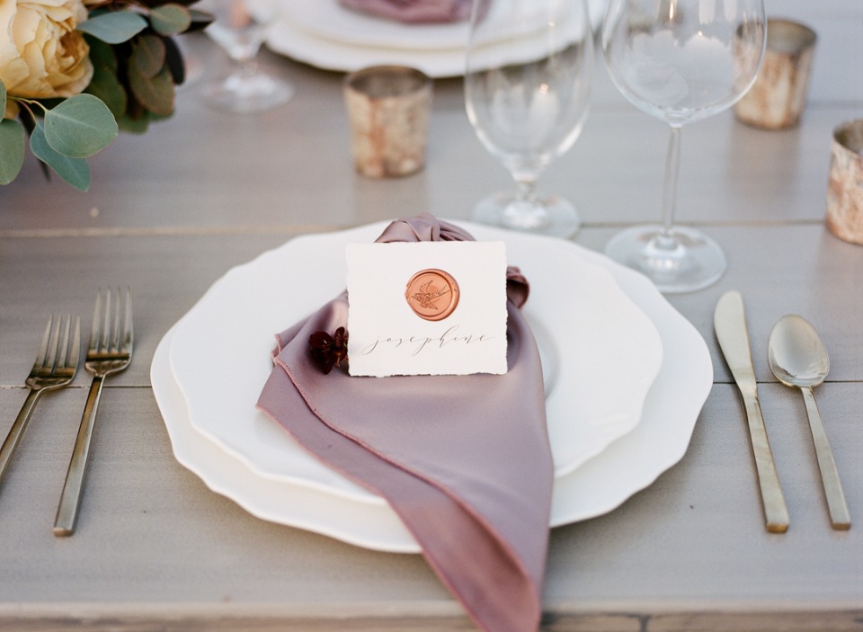 Elegant place setting with mauve napkin and floral seal detail
