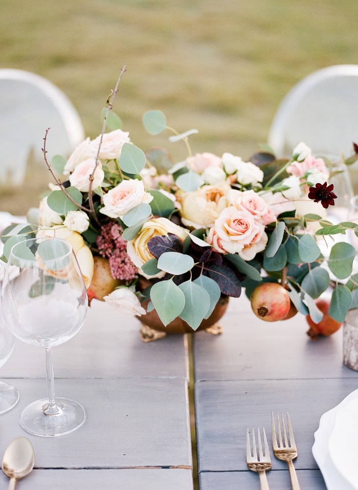 Elegant floral centerpiece with roses and pomegranates on a table