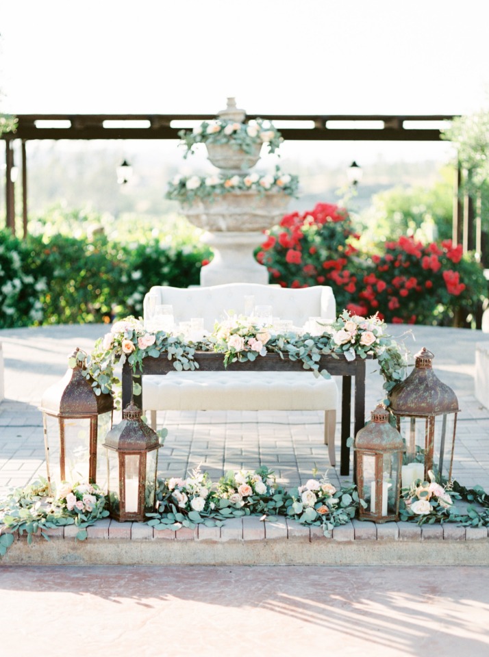 sweetheart table draped in flowers with giant lanterns