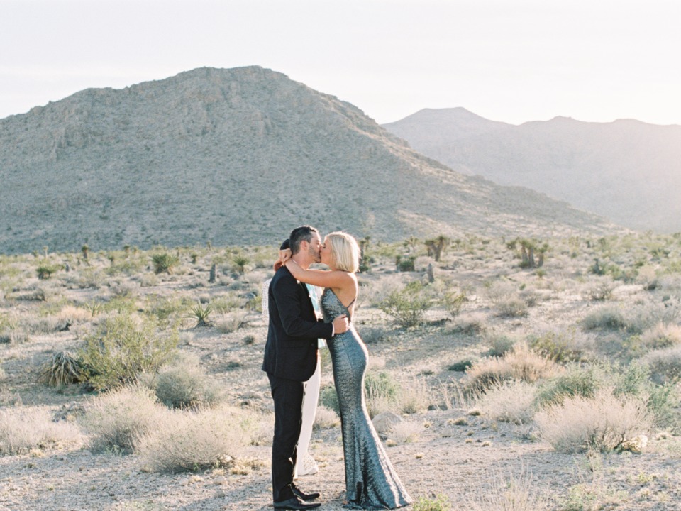 Couple kissing in a desert wedding ceremony with mountain view