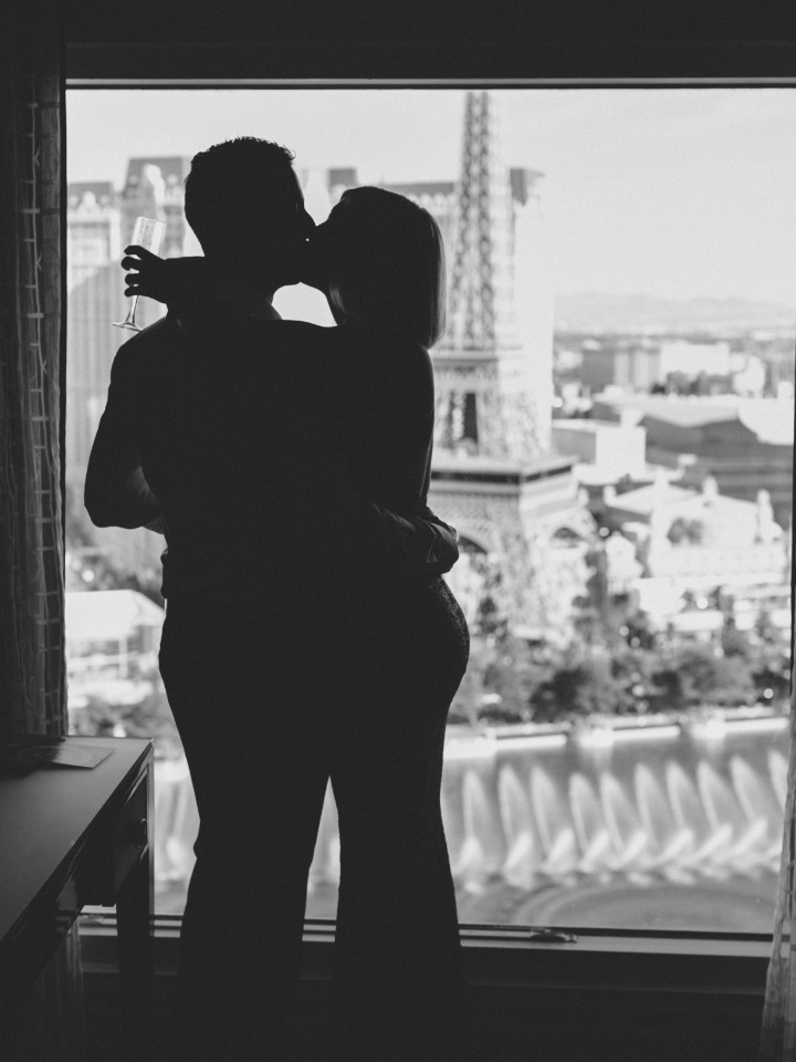 Couple kissing in silhouette by window with Eiffel Tower view