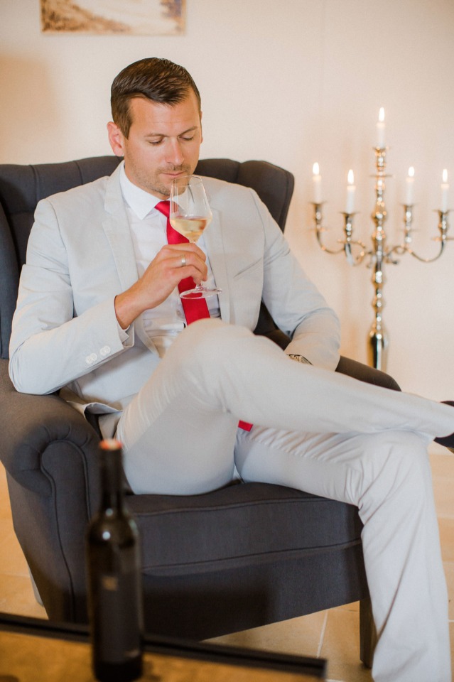 groom in sandstone suit with red tie