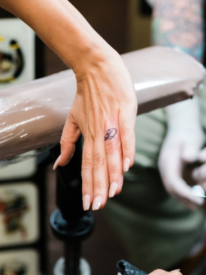 Woman's hand with a small tattoo on finger in a tattoo shop