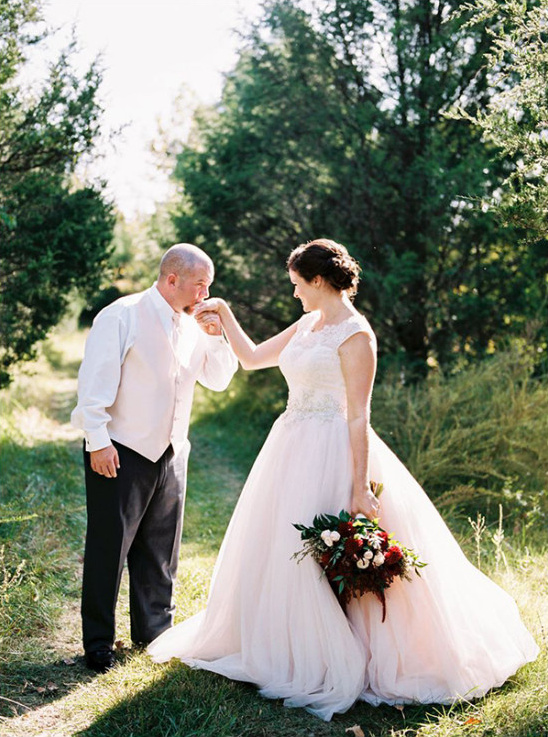 Groom kisses brides hand at outdoor wedding ceremony